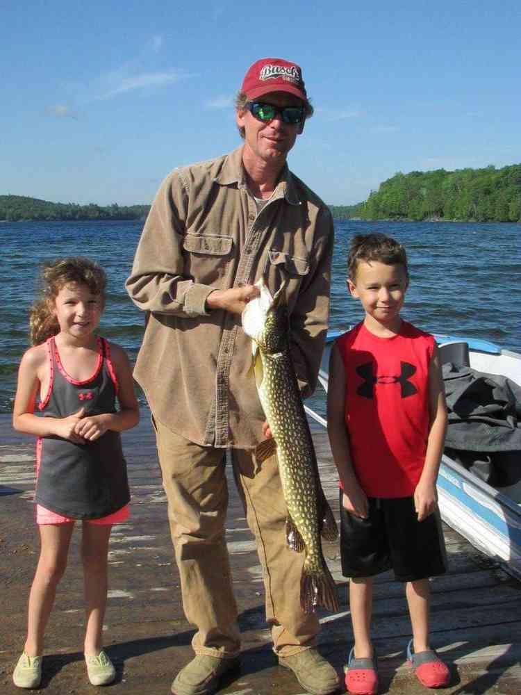 A man with two kids holding a pike