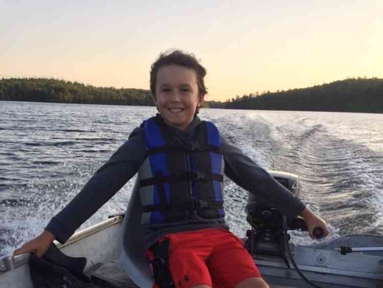 A boy happily driving a boat