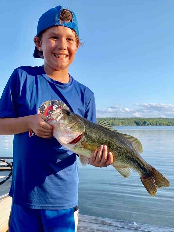 A smiling boy holds up a bass